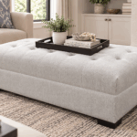 Sorrent Ottoman with light neutral tufted upholstery and dark wooden feet